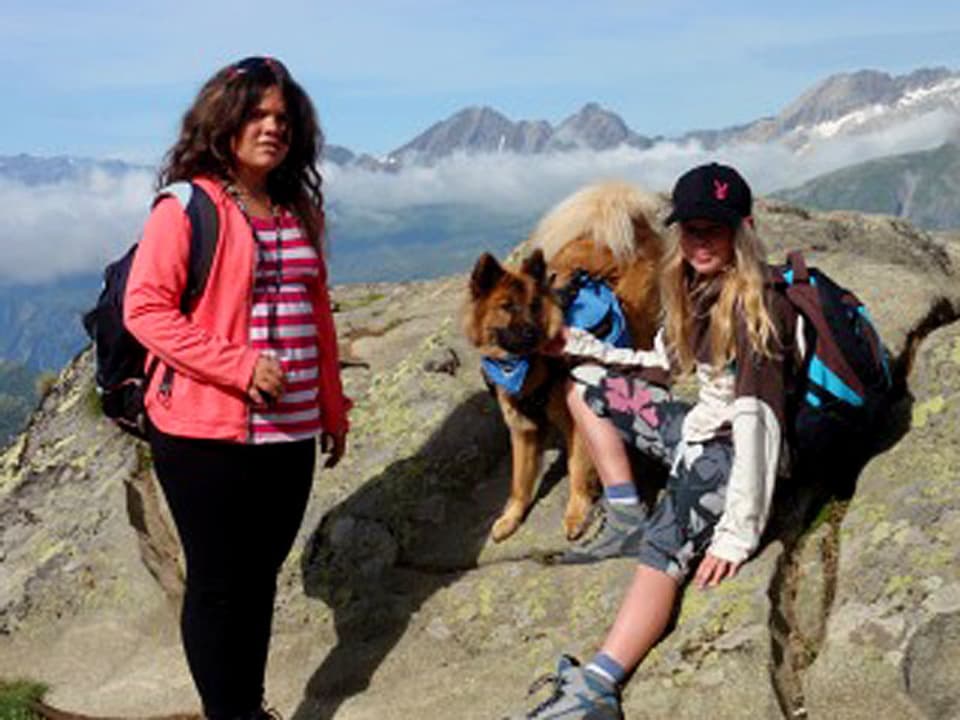 Frauen mit Hunden auf Berggipfel.