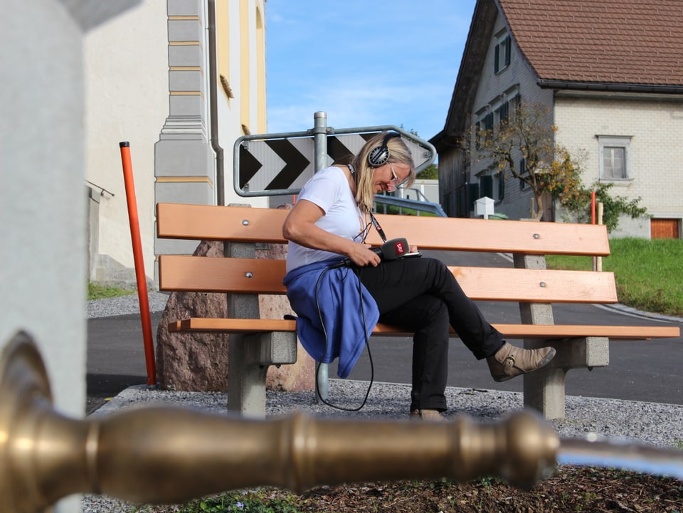 Radio SRF 1-Redaktorin Christine Hubacher sitzt auf einer Bank und überfliegt ihre Notizen.