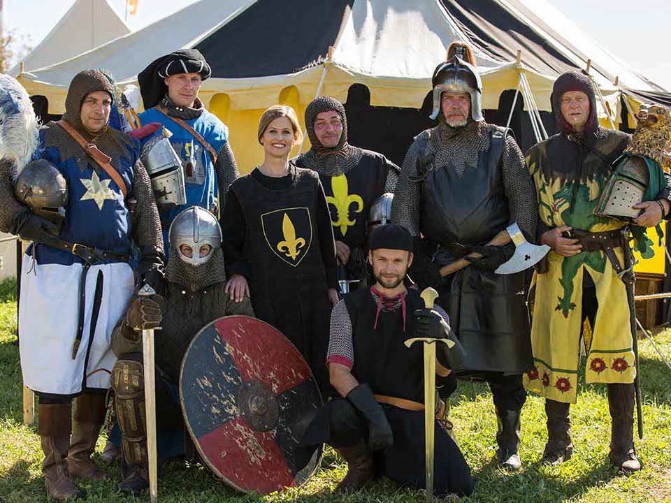 Eine Gruppe von Leuten mit Ritterkleidern, Helmen und Waffen.