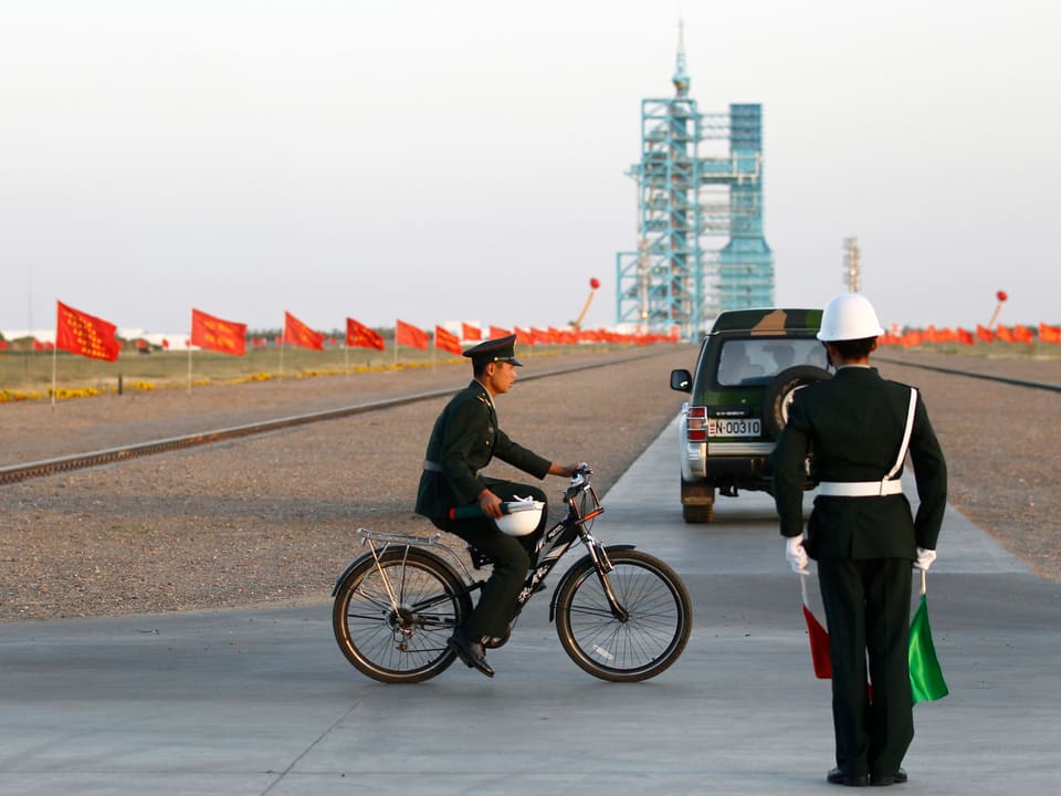 Mann in Uniform fährt mit dem Velo über das Areal vor dem Raketenstartplatz.