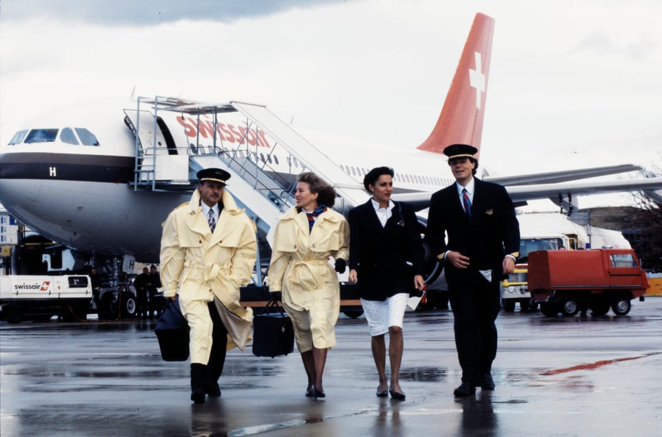 Zwei Frauen und zwei Männer in Uniform vor einem Swissair-Flugzeug. Zwei von ihnen tragen helle Mäntel