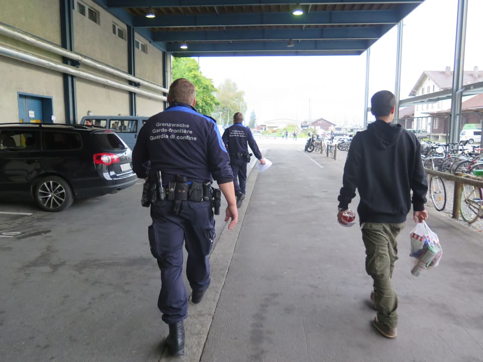 Zwei Grenzwächter und ein Flüchtling auf dem Weg ins alte Postgebäude.
