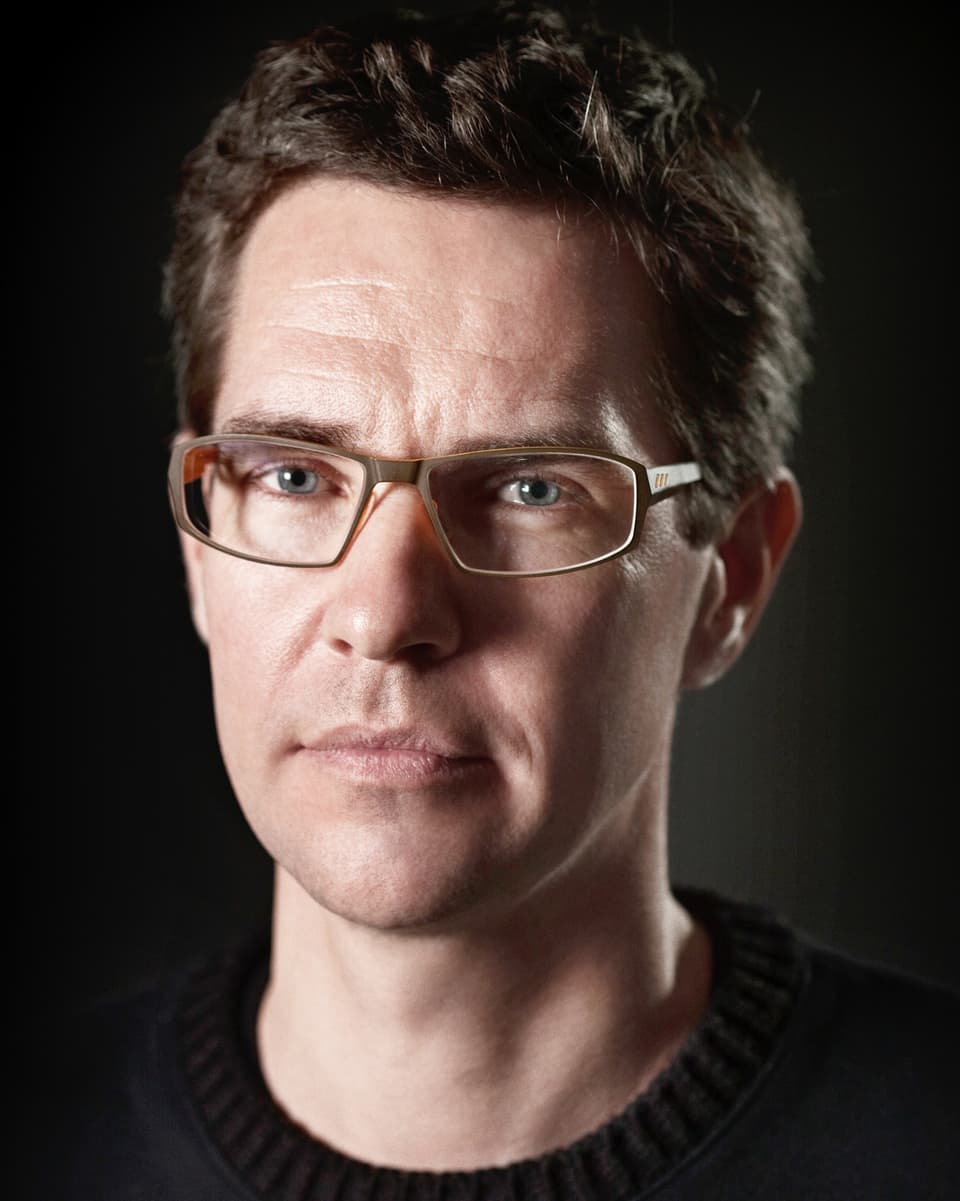 Porträt von einem Mann mit Brille und schwarzem Pullover.