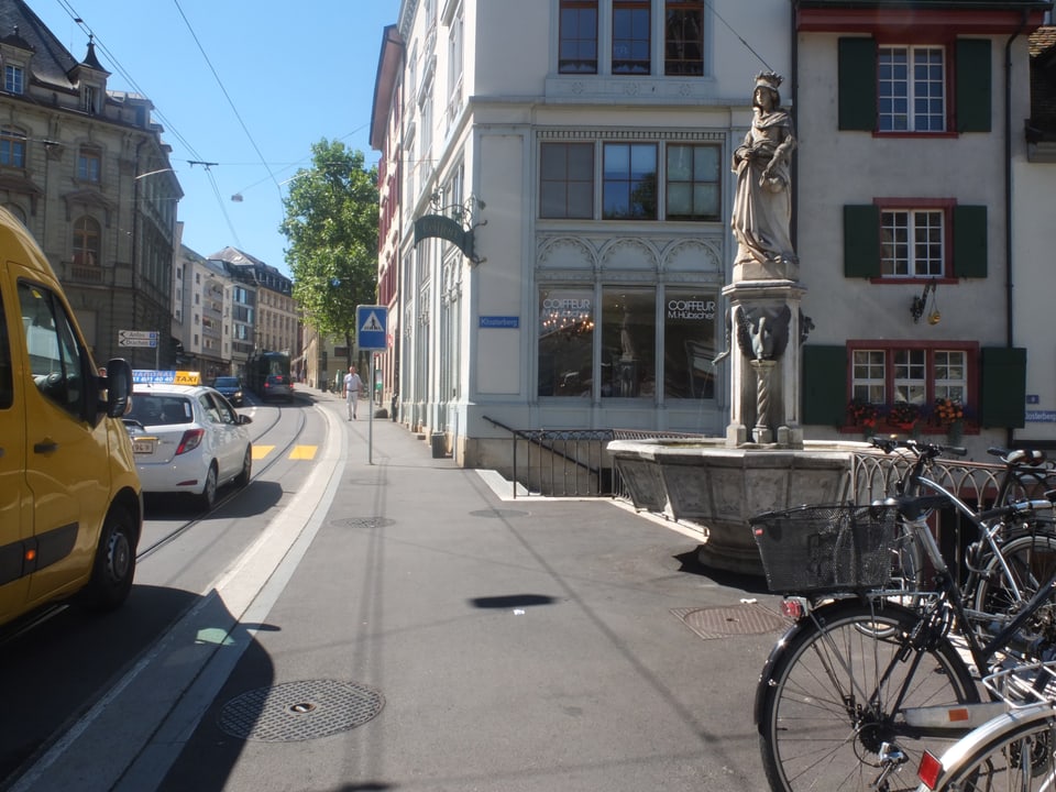 Elisabethenbrunnen, links davon die viel befahrene Strasse und ein paar abgestellte Velos im Vordergrund. 