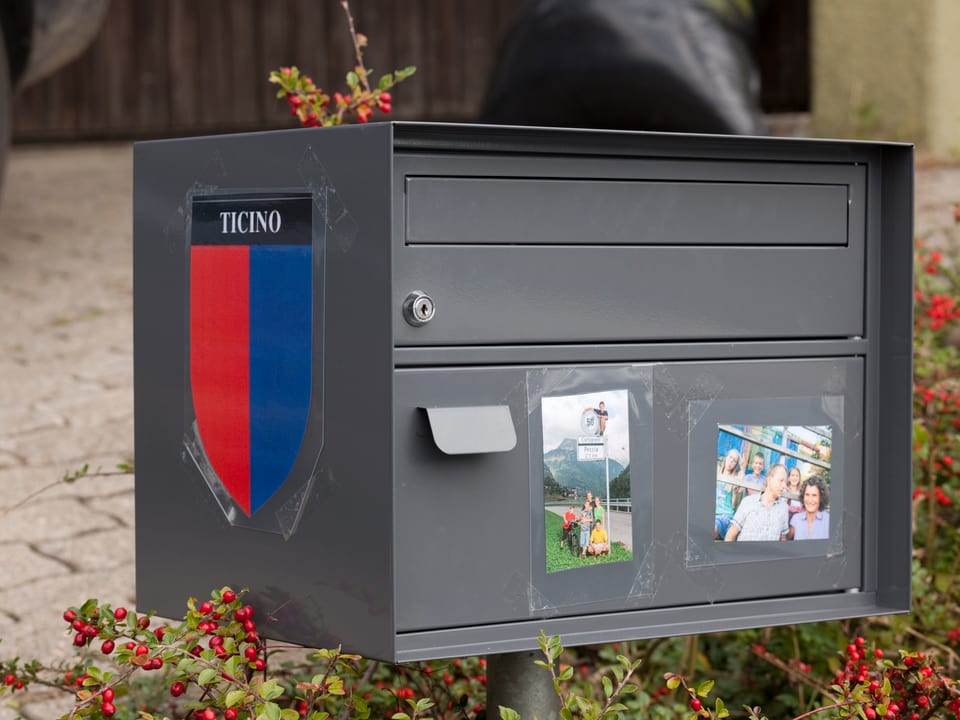 Briefkasten mit aufgeklebtem Tessiner Wappen und den Fotos von beiden Familien.