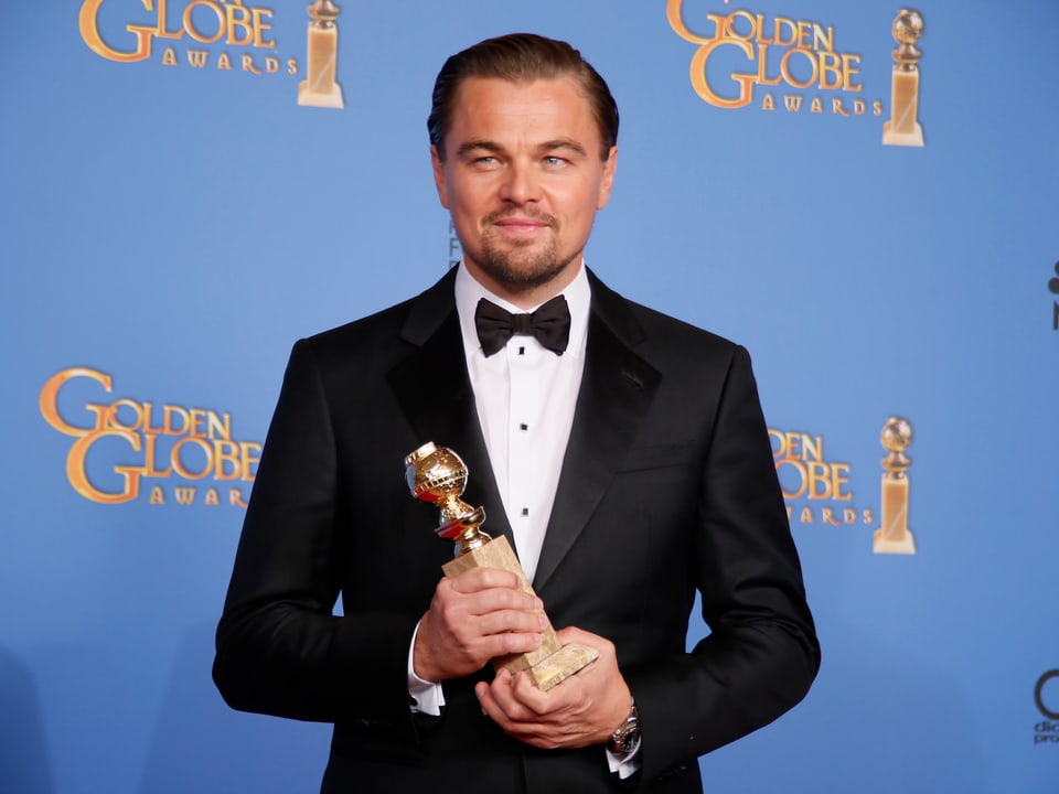 Leonardo Di Caprio hält seinen Golden Globe in der Hand.