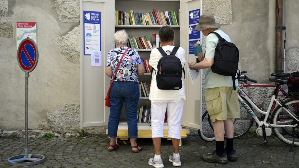 Menschen stehen vor einem Bücherregal auf der Strasse.