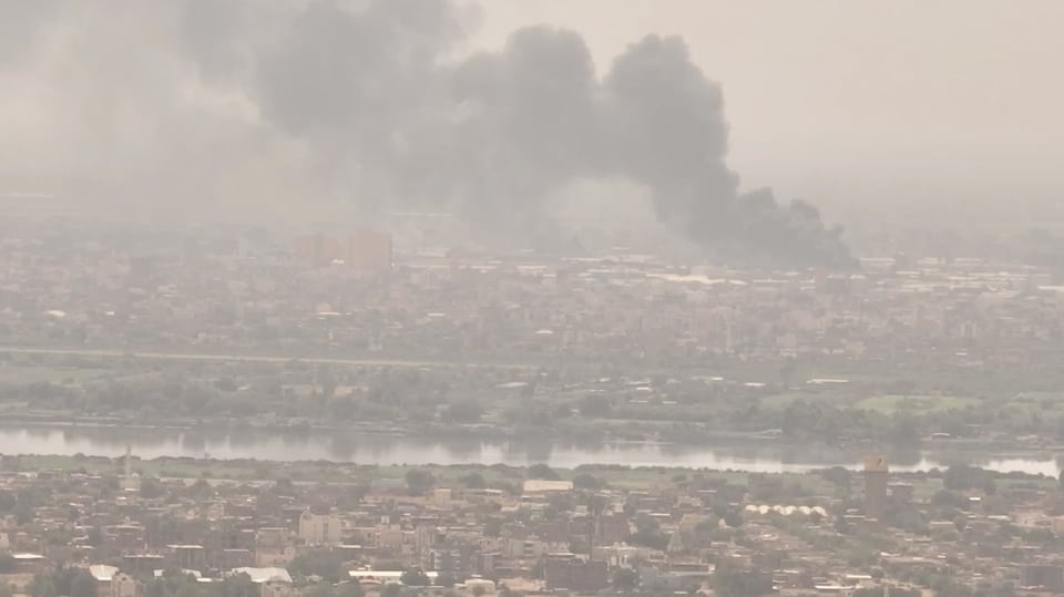 Die Stadt Khartum aus Distanz, auf dem Bild ist der Fluss zu sehen und eine Rauchwolke, die aufsteigt.