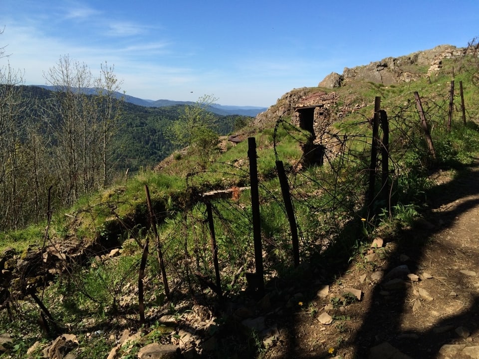 Hügellandschaft mit Schützengraben im Vordergrund.