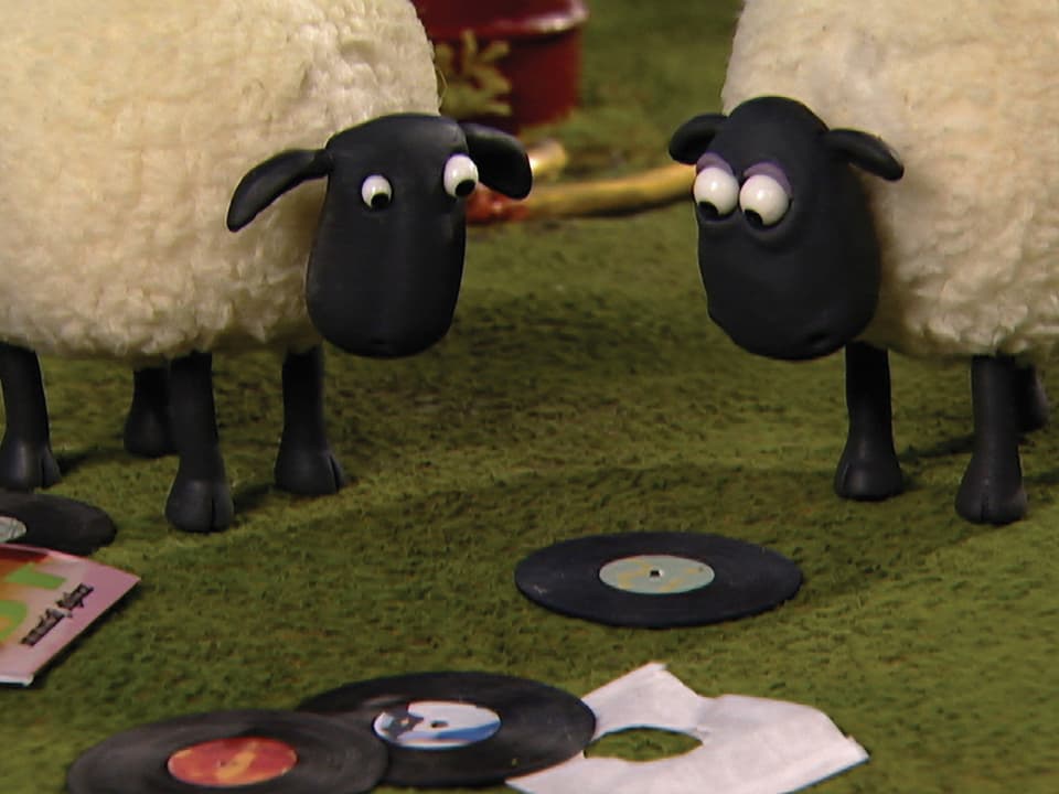 Zwei Schafe aus Knetmasse schauen auf eine Vinyl-Platte.