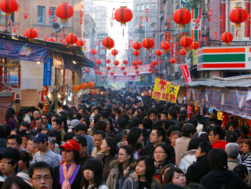 Menschenmenge auf einer Einkaufsstrasse mit festlichen Lampions