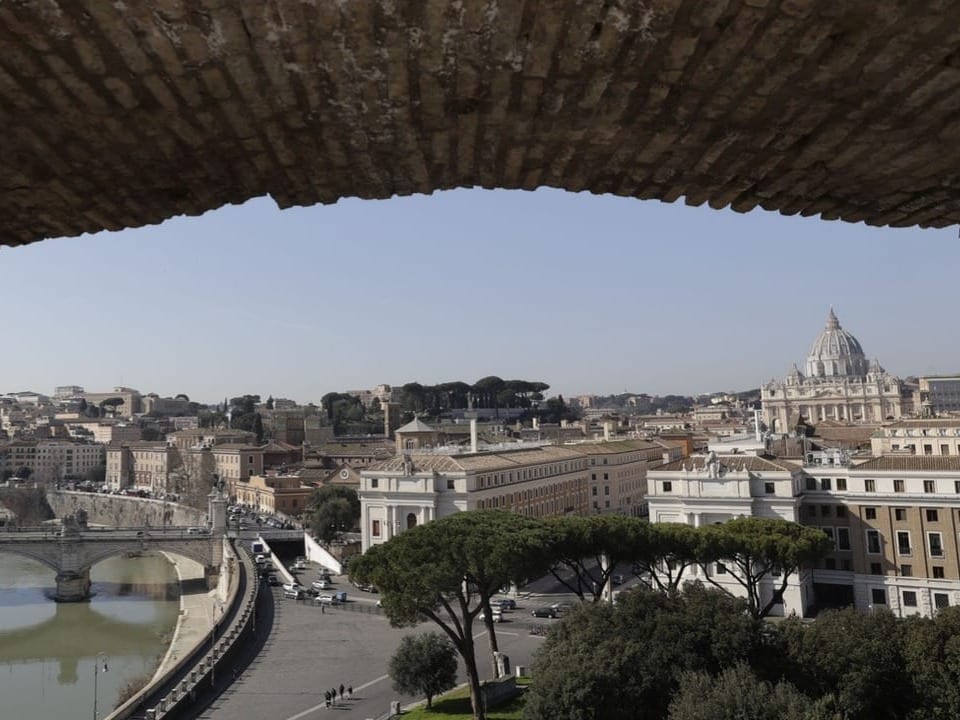 Ausblick auf Rom mit Vatikan im Hintergrund, gesehen durch einen Bogen.