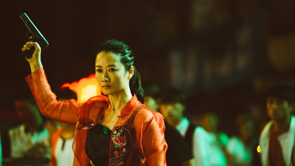 Hauptdarstellerin Zhao Tao hält im Rahmen ihrer Rolle in «Ash Is Purest White» eine Pistole in die Höhe.