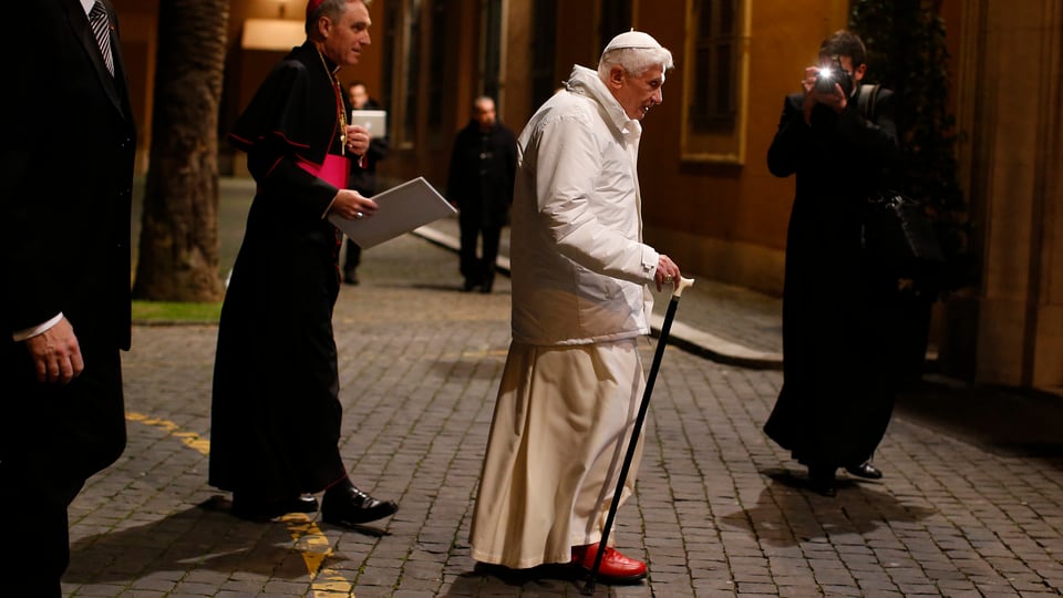Der Papst überquert mit Hilfe eines Gehstocks eine Strasse in der Altstadt von Rom.