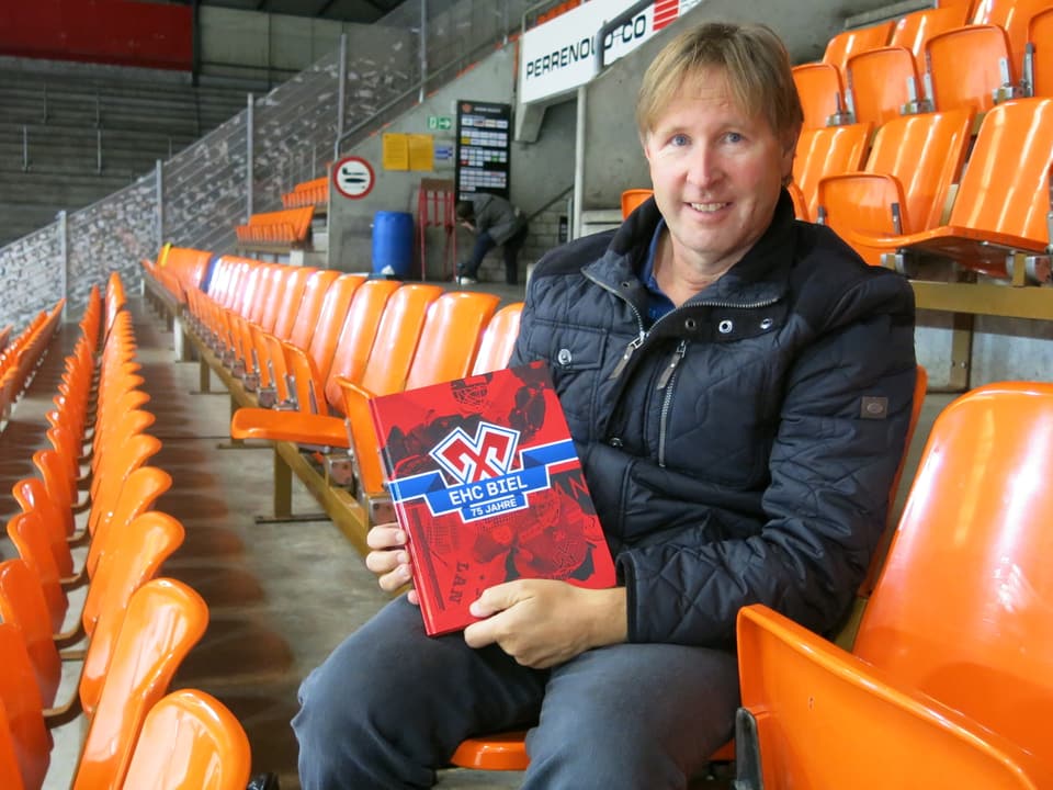 Beat Moning sitzt mit einem Buch im Eisstadion Biel