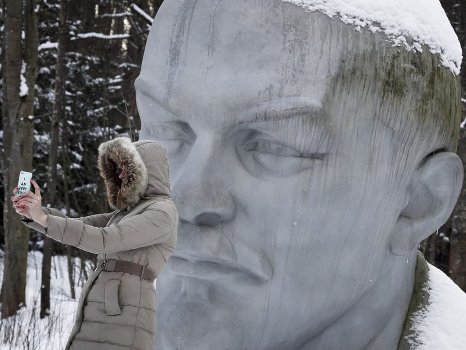 Rechts gross hinten ein steinerner Kopf Lenins