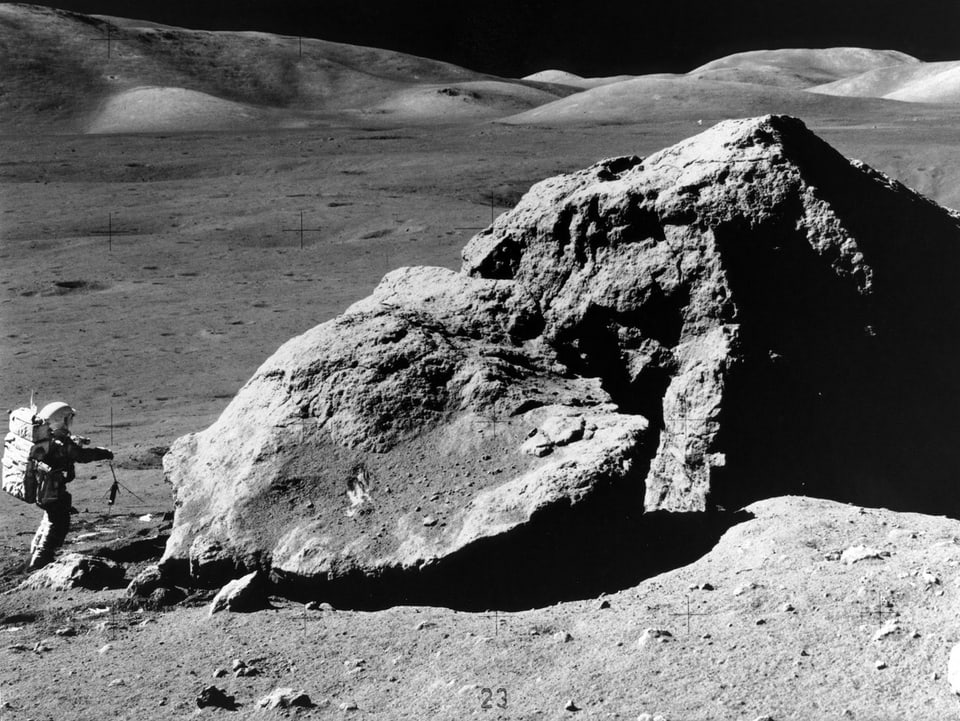 Mann vor einem Stein auf dem Mond.