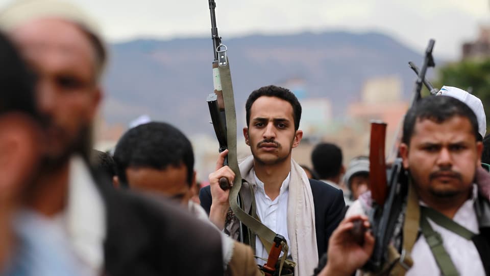 Huthi-Rebellen halten ihre Gewehre in die Luft.