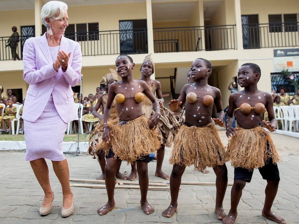 Christine Lagarde tanzt mit afrikanischen Kinder in traditioneller Tracht. (Kamerun, 2016)