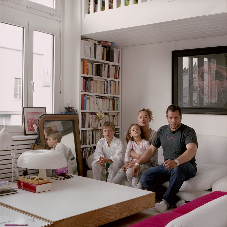 Eine Familie sitzt in einem Wohnzimmer auf dem Sofa.