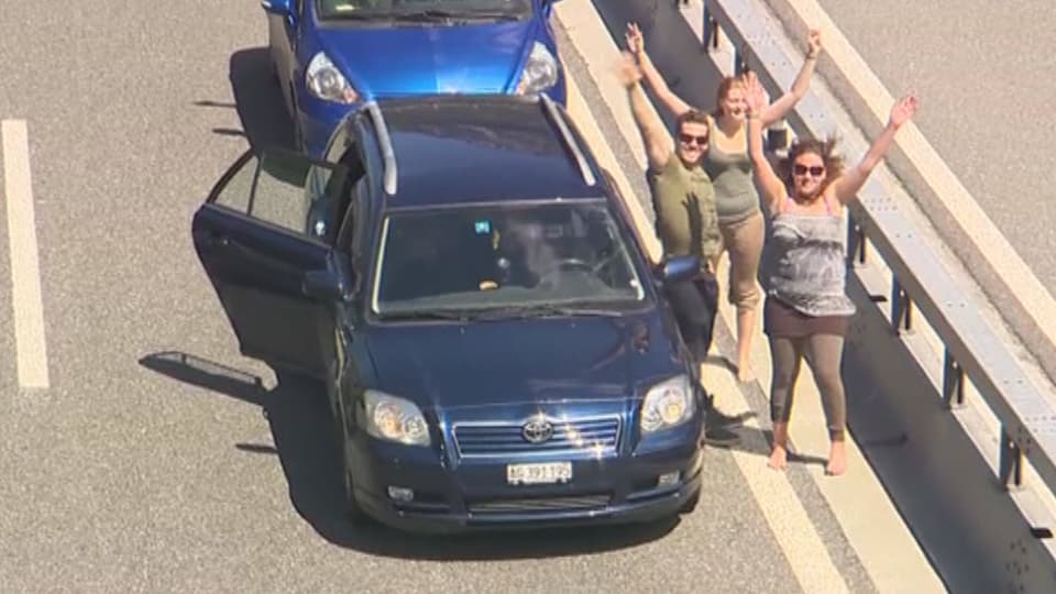 Leute winken auf der Autobahn neben ihrem stehenden Auto. 