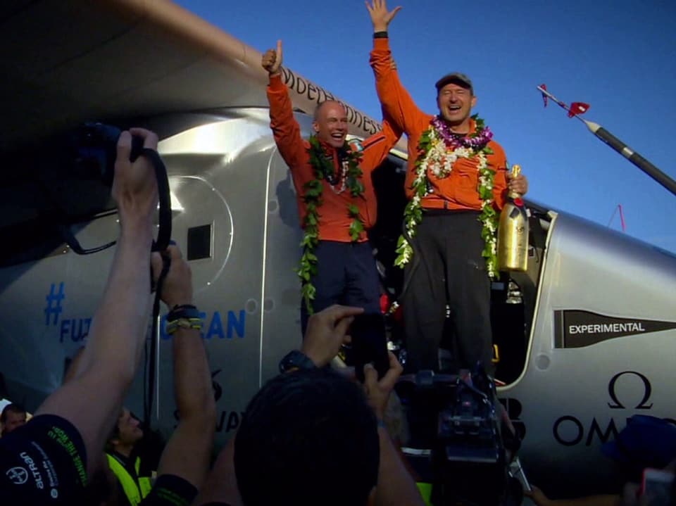 Zwei Männer feiern die Ankunft des solarbetriebenen Flugzeugs in Hawaii.
