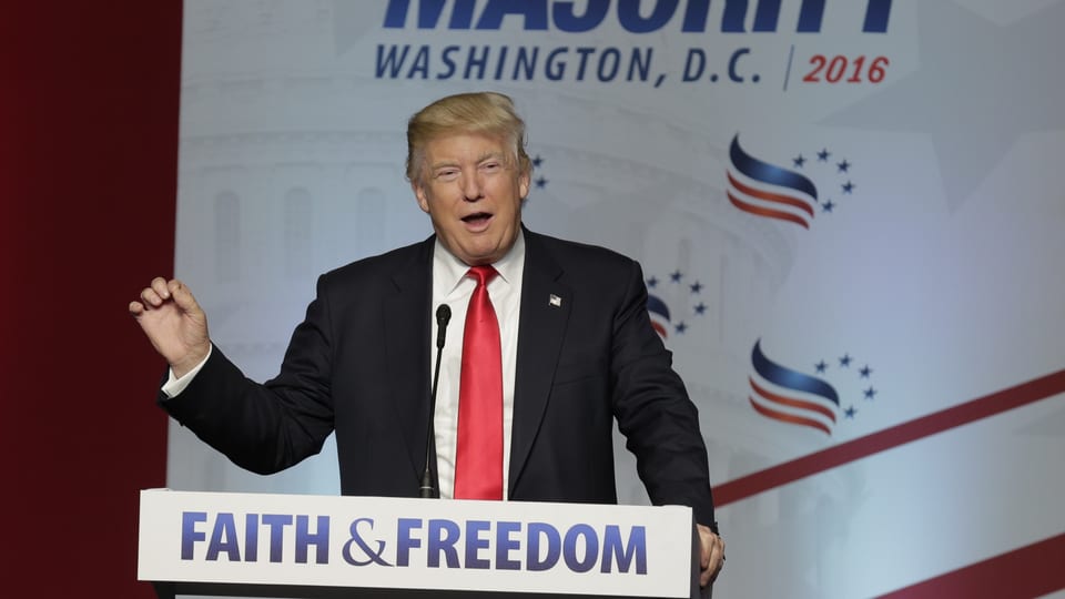 Donald Trump an einem Rednerpult, auf dem "Faith & Freedom" steht. 