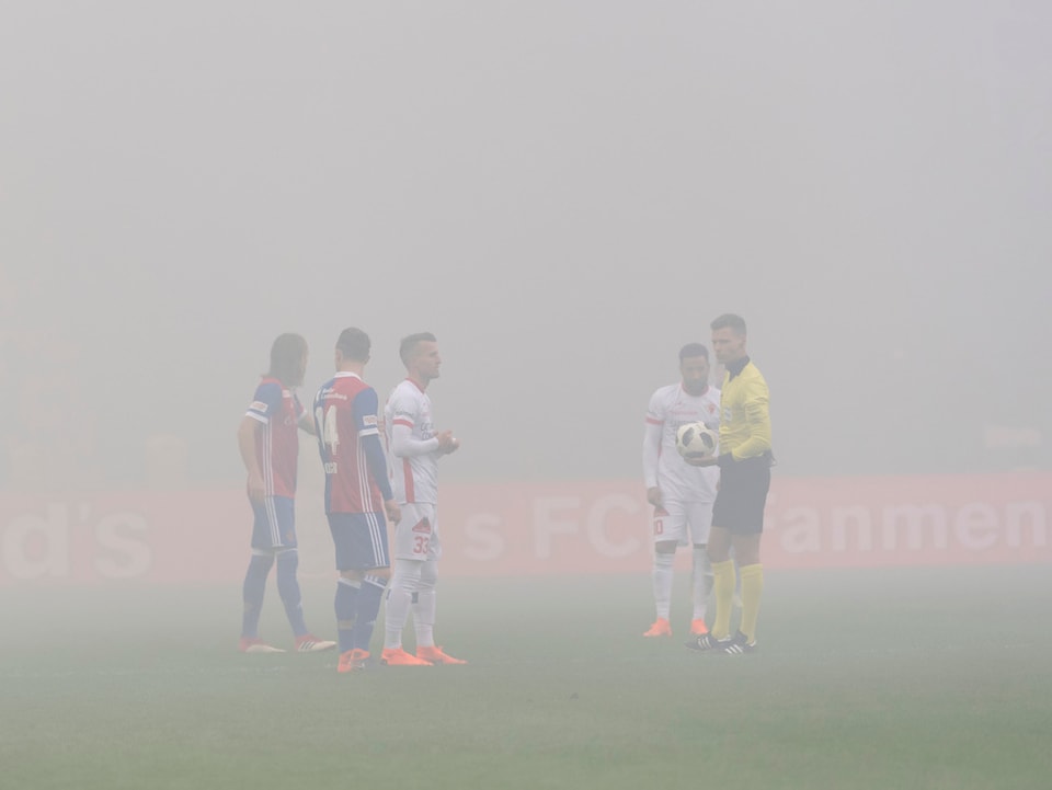 Die Spieler von Basel und Sion stehen in dichtem Rauch.
