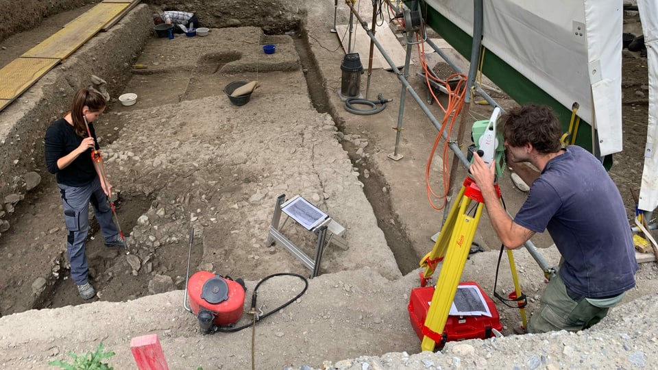 Eine Archäologin und ein Archäologe bei Ausgrabungsarbeiten