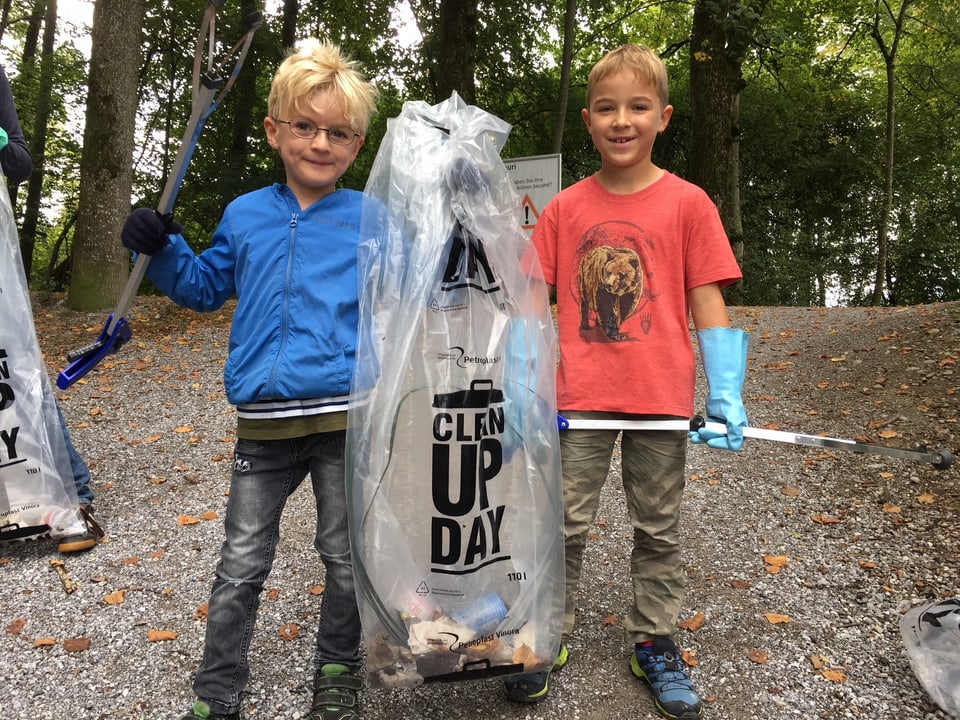 Kinder mit Abfallsäcken im Wald.