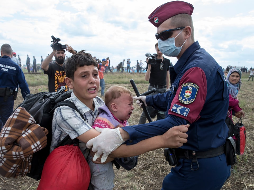 Ein ungarischer Polizist hält bei Röszke einen Flüchtlingsbub fest. 