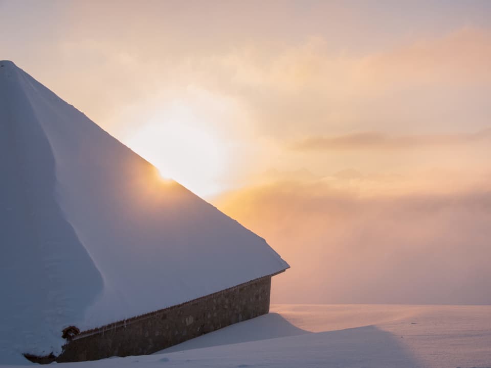 Sonnenaufgang über einer Hütteim Schnee