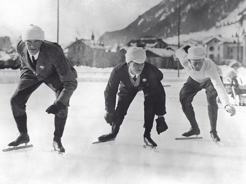 Drei Eiskunstläufer in Alltagskleidung, kurz vor dem Start.