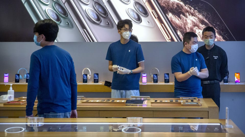 Mitarbeiter eines Apple-Stores in Peking tragen Mundschutz