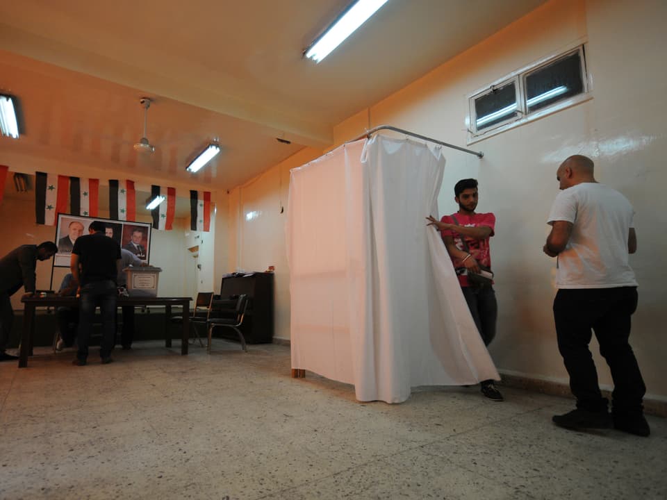 Junger Mann tritt aus Wahlkabine in Damaskus heraus
