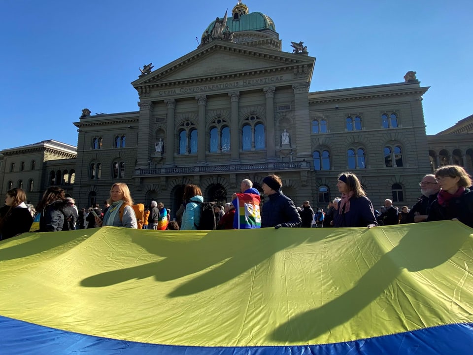 Personen auf dem Berner Bundesplatz mit einer grossen Ukraine-Fahne.