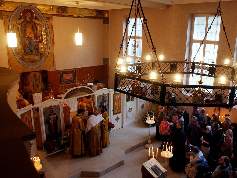 Geistliche stehen vor der Ikonostase im Altarraum. 