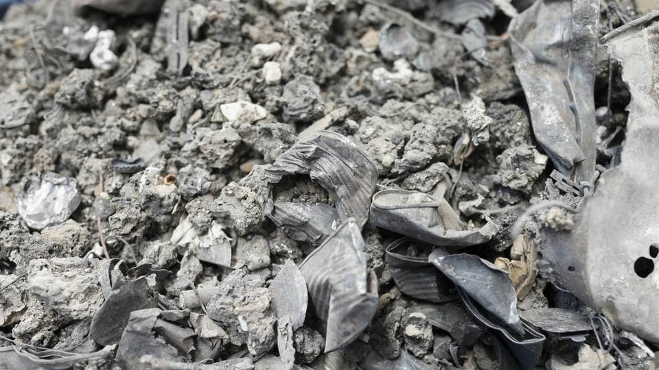 Graue trockene Masse mit zahlreichen Metallteilen