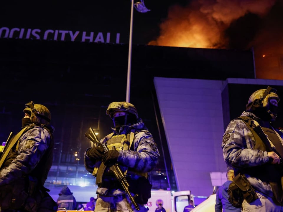 Police officers in front of burning building.