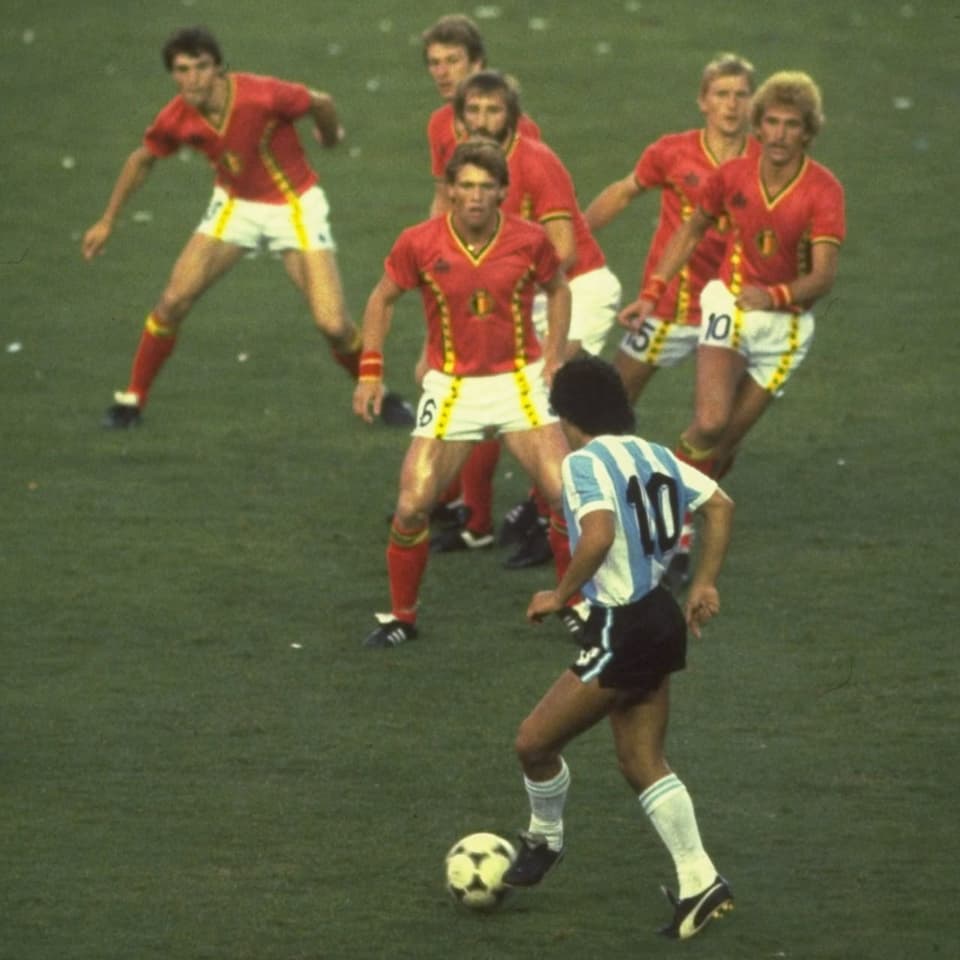 Foto: Maradona im Vordergrund am Ball, im gegenüber 6 belgische Spieler nah beieinander