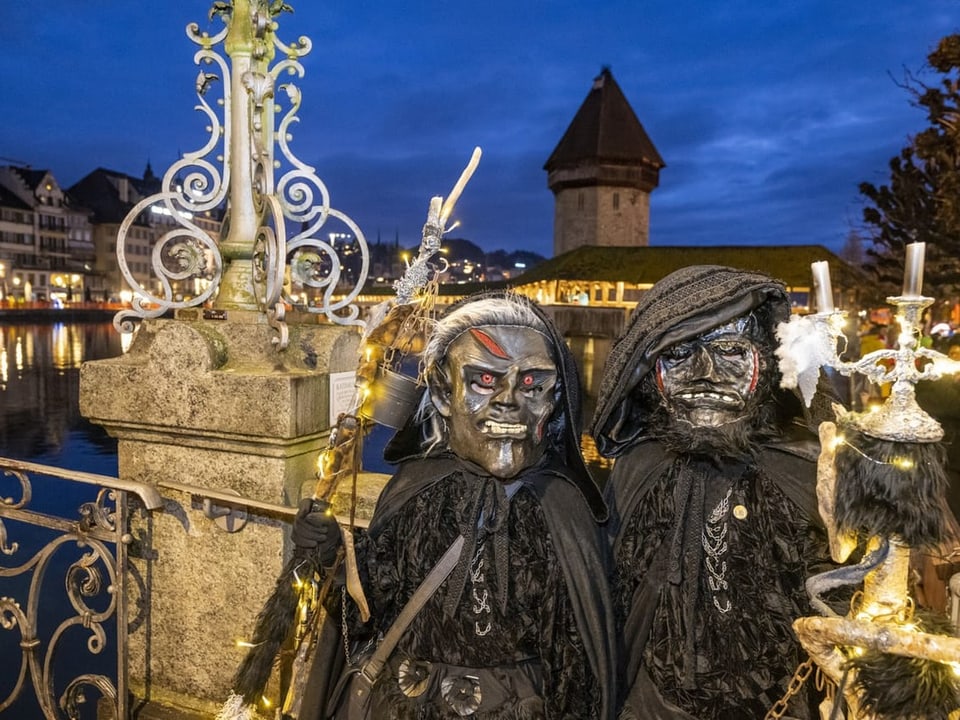 Gestalten mit düsterer Maske posieren in den frühen Morgenstunden vor dem Luzerner Wahrzeichen.