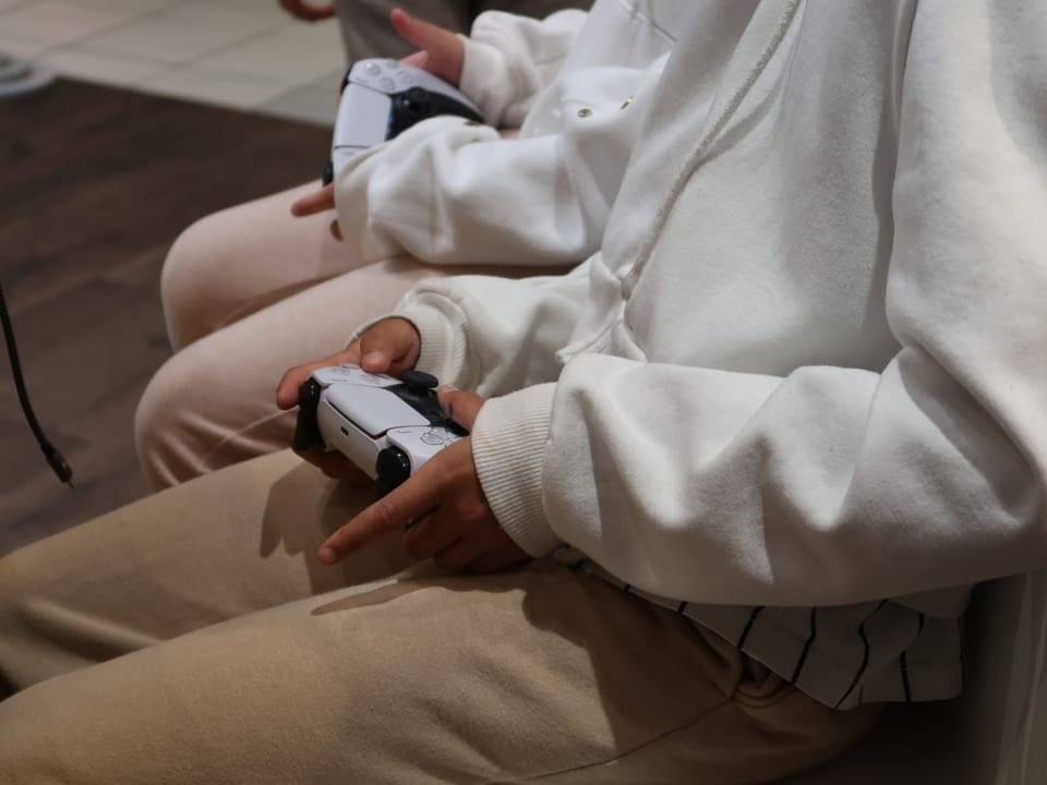 Zwei Mädchen halten Spielkonsolen in der Hand.