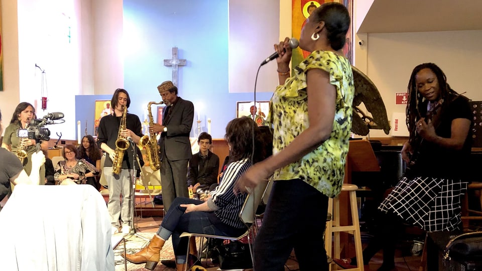 Frauen und Männer musizieren in einer Kirche.