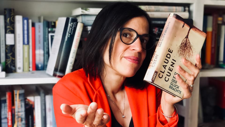 Annette hält das Buch  «Der Mann, der das Glück bringt» von Claude Cueni in den Händen und schaut fragend drein.