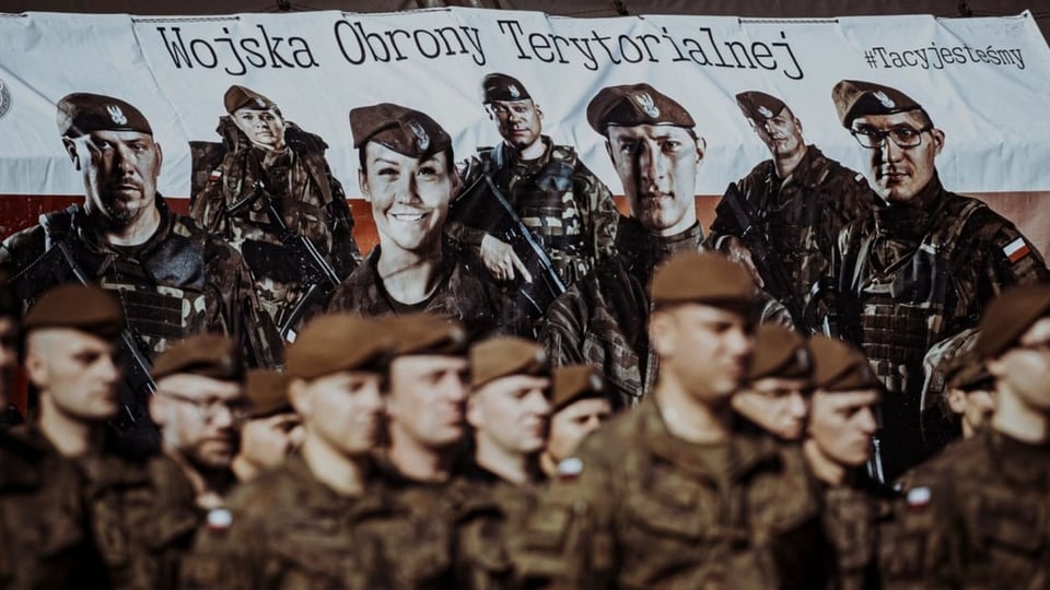 Angehörige der Territorialverteidigung posieren vor einem Banner.