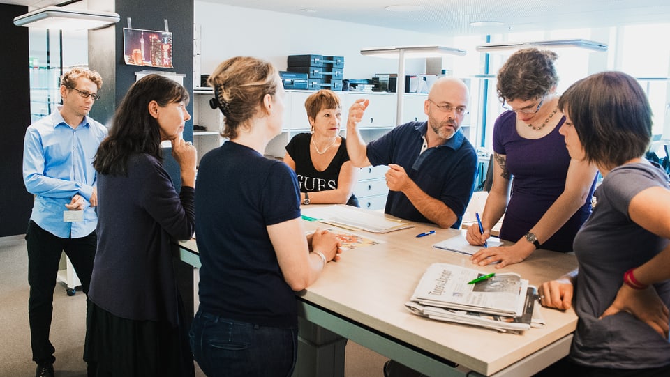 Mehrere Personen diskutieren an einem Stehtisch