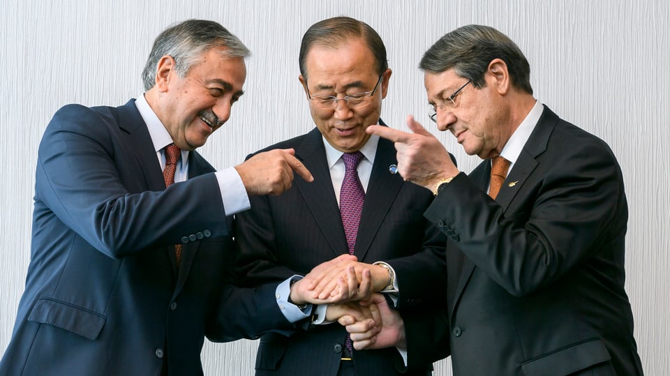 Drei Männer geben sich die Hände.