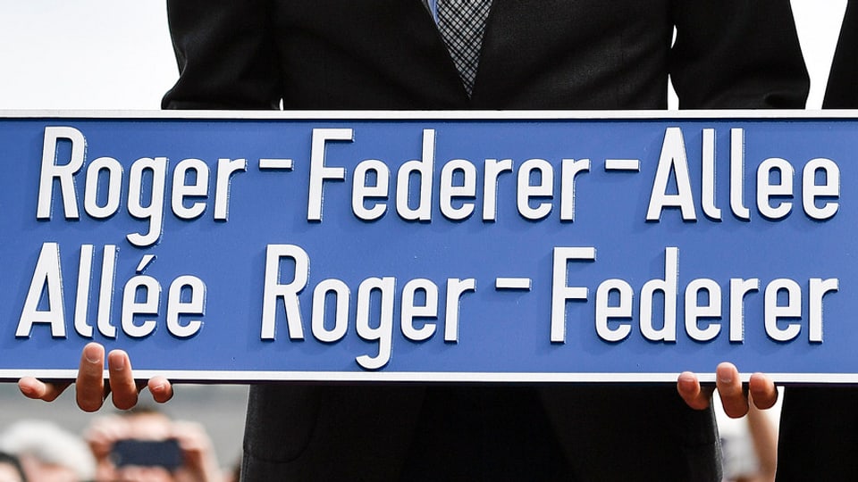 Federer mit Strassenschild in der Hand.