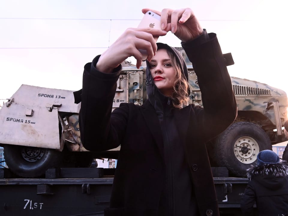 Junge Frau schiesst Selfie mit Panzer.
