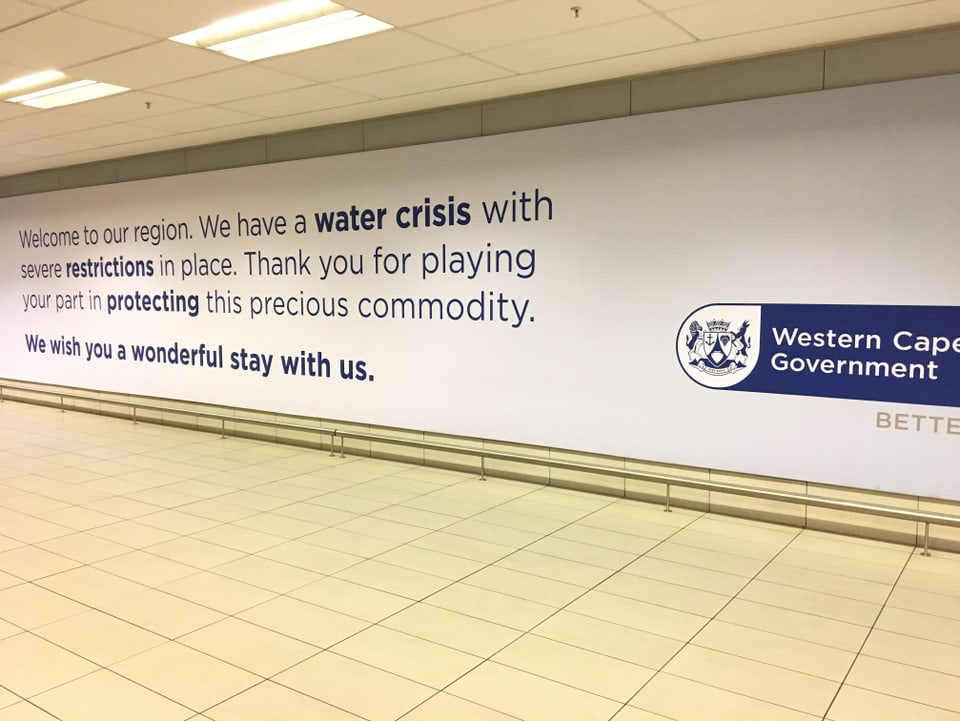 Plakat an einer Wand mit dem Aufruf, möglichst wenig Wasser zu brauchen.